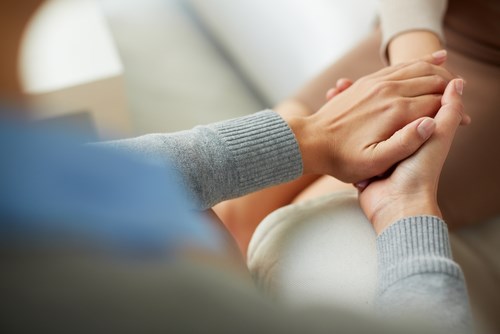 Woman reassuring her friend by holding her hand during IVF appoinment